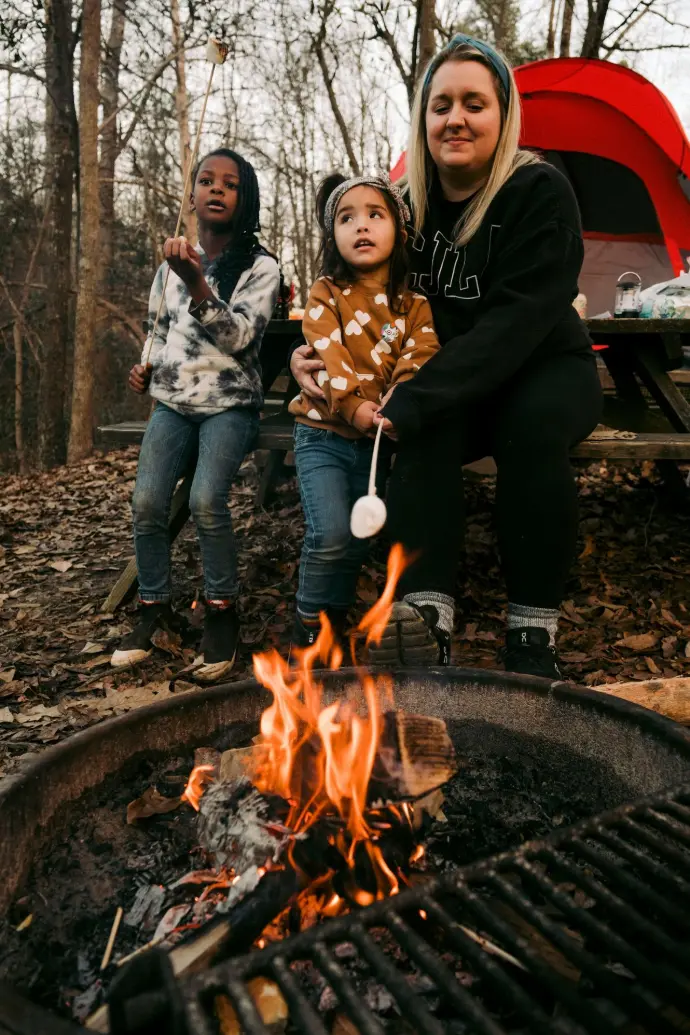 a woman and two children cooking on a grill